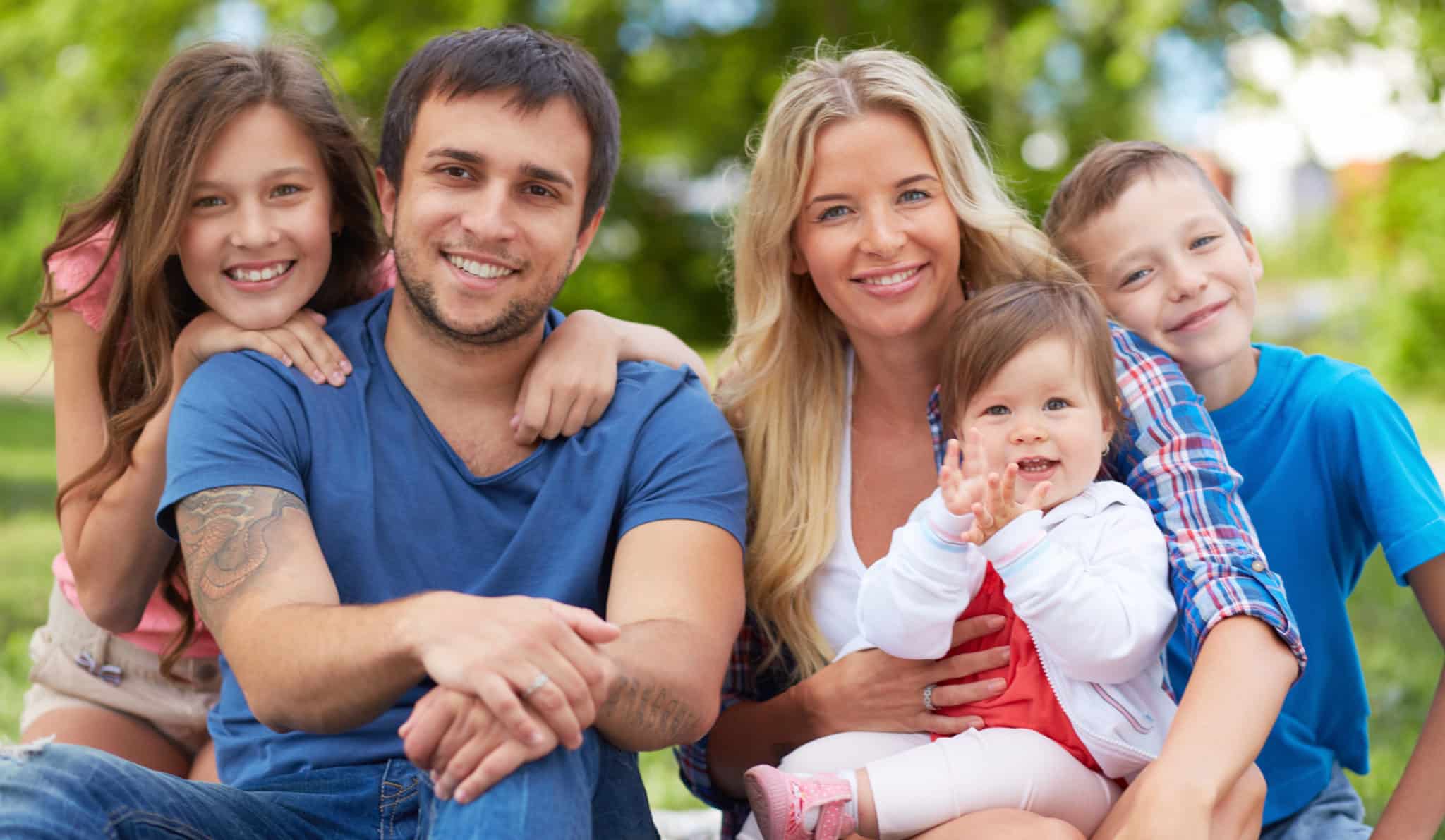 Happy family of five with beautiful smiles sitting outside